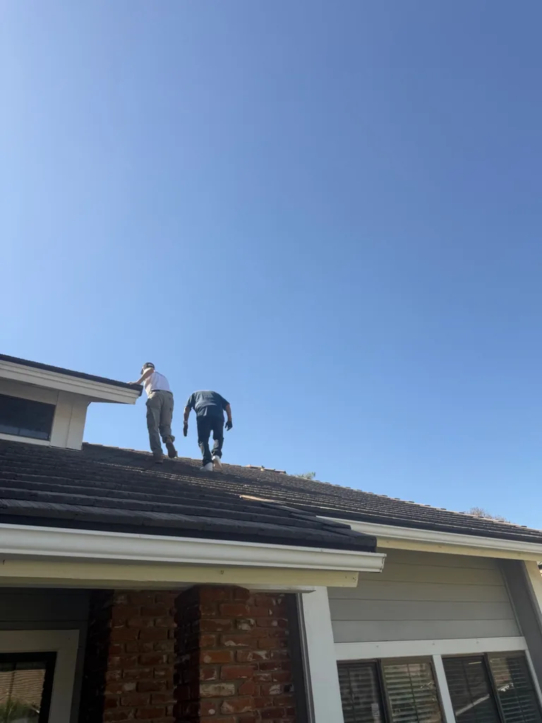 Solar crew installing panels on a tile roof with an expansive blue sky backdrop