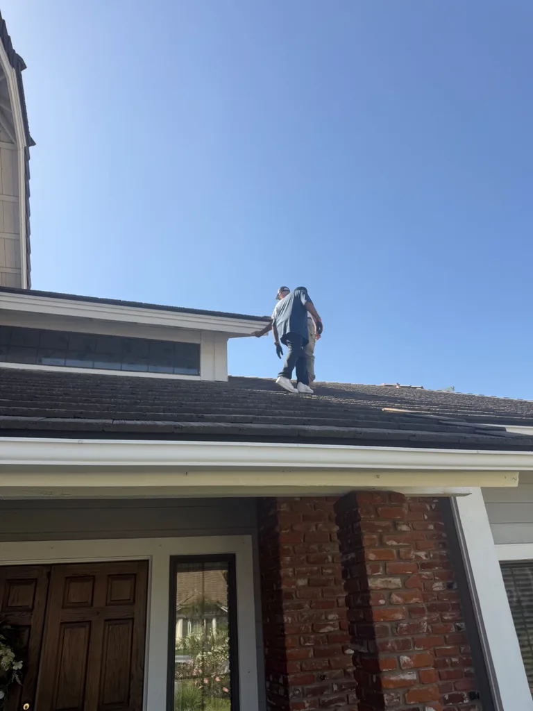 Solar installation crew members walking across a dark tile roof under a clear blue sky
