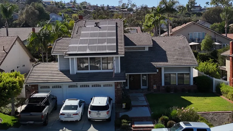 Two-story residential home with solar panels on a brown tile roof
