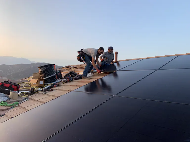 Crew positioning a panel on a tile roof