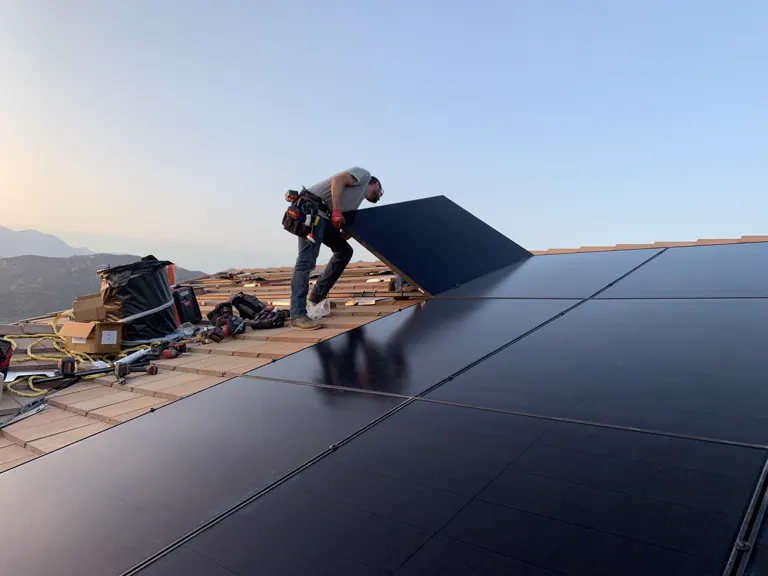 Installer lifting a panel at golden hour